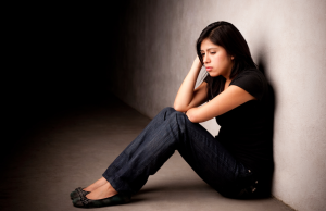 Person sitting on the floor, against a wall, looking stressed out