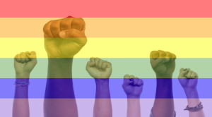 Fists are in the air, overlayed with a rainbow flag